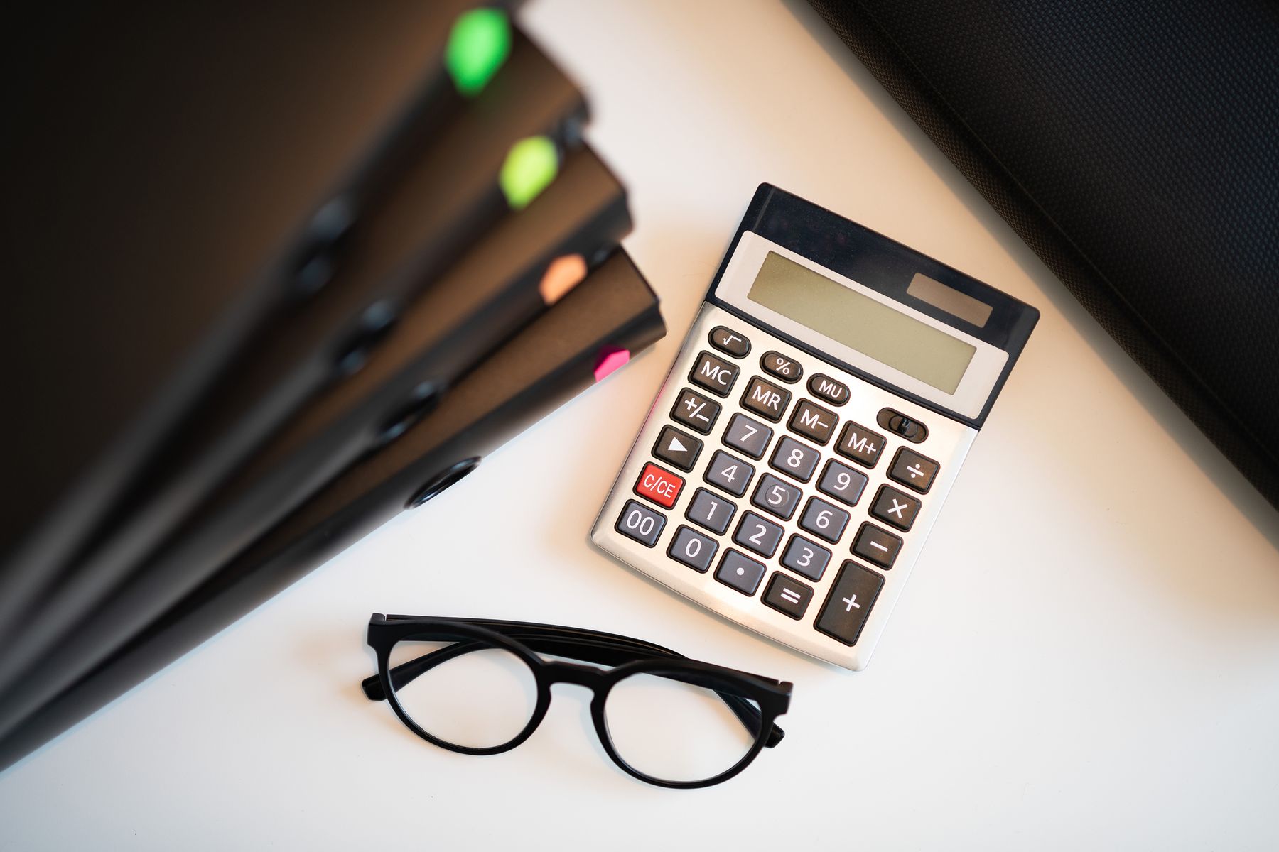 Calculator, glasses, and financial folders arranged on an office desk