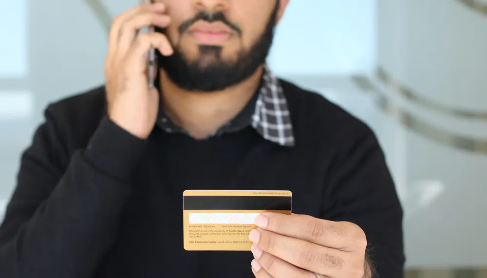 Businessman speaking on a phone while holding a credit card.